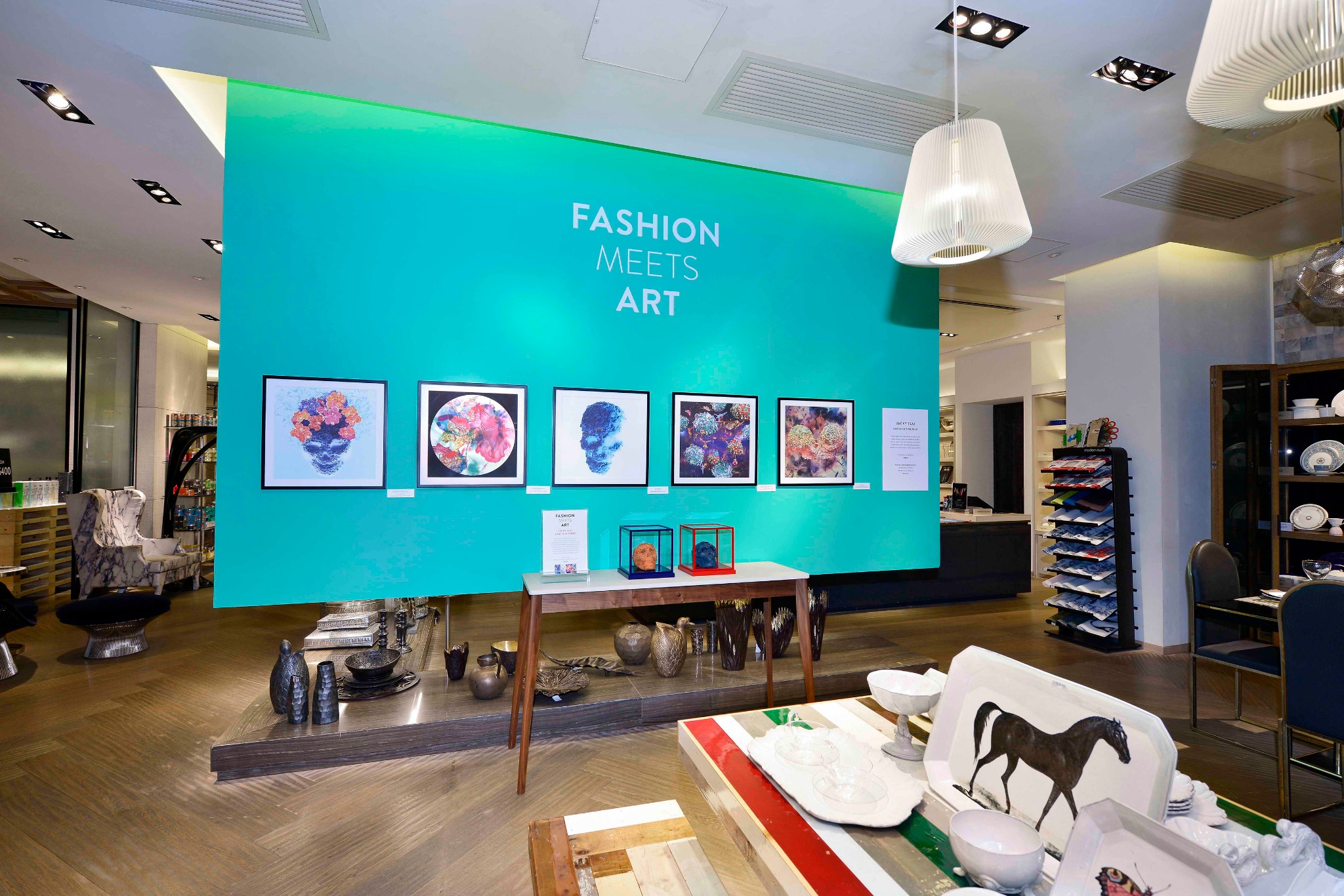 Jacky Tsai’s framed prints displayed on a turquoise Fashion Meets Art wall within Lane Crawford’s homeware space